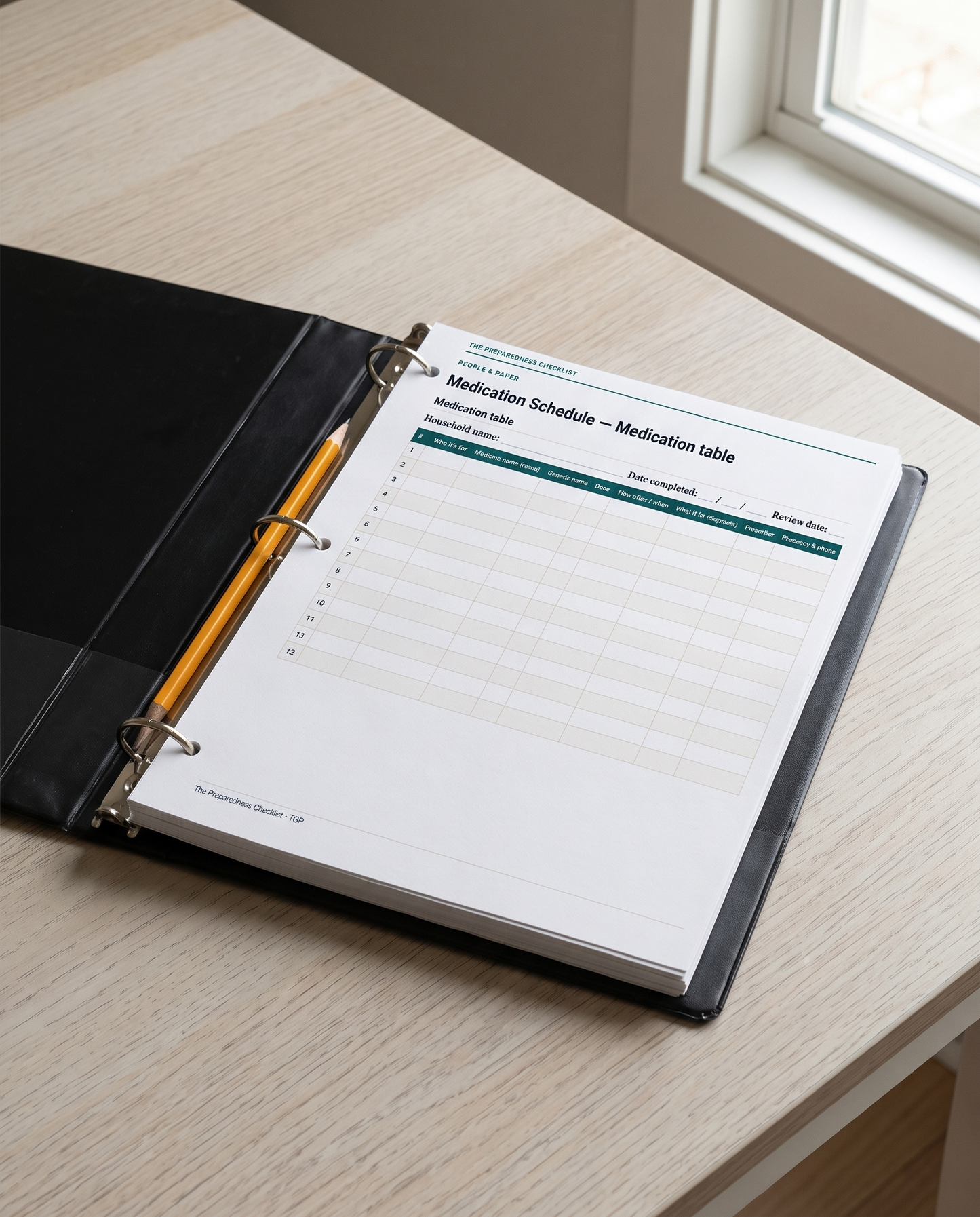 Printed pages of the workbook in a ring binder, open at the medication table, with a pencil